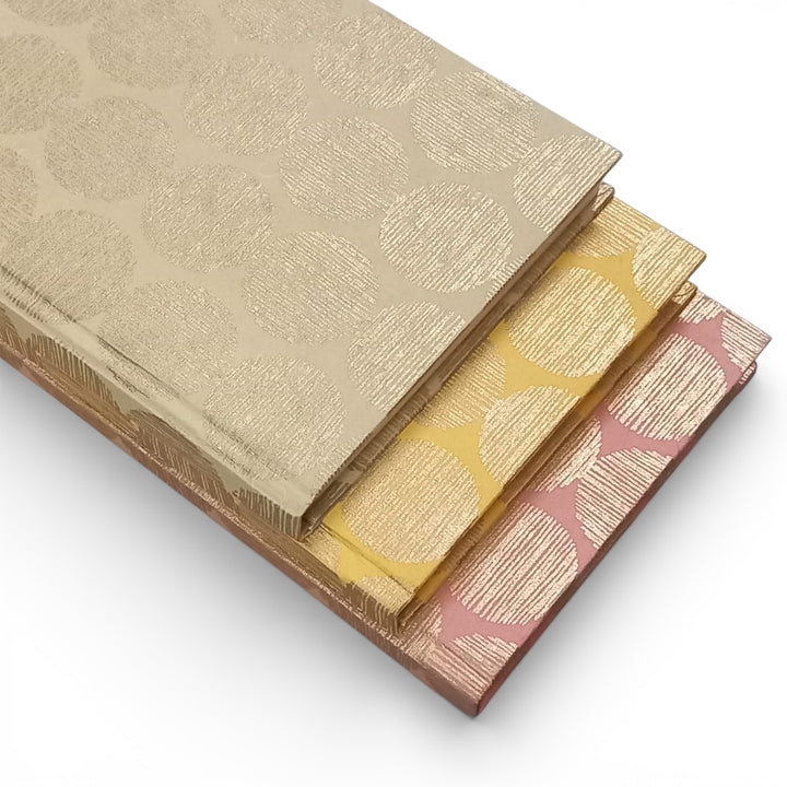 Three hardcover notebooks layered on top of each other with different colours all with a geometric sunrise cover design on a white background