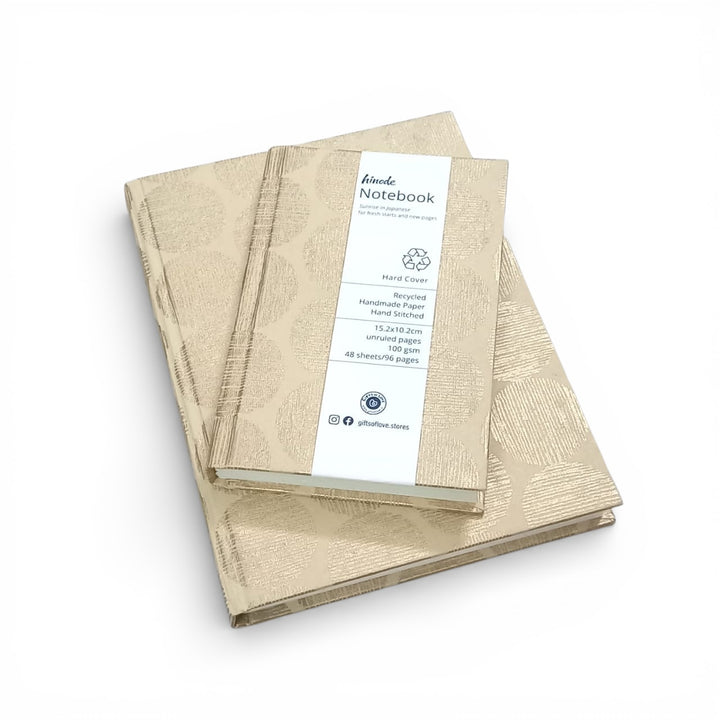 Beige notebook with a label and a geometric sunrise pattern in gold on a white background