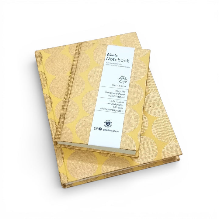 2 Yellow notebooks with a gold geometric sunrise patterned cover on a white background