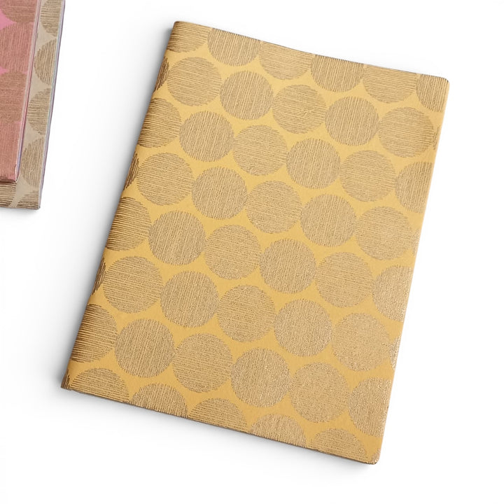 Handmade paper notebook with gold circular sunrise pattern on a white background