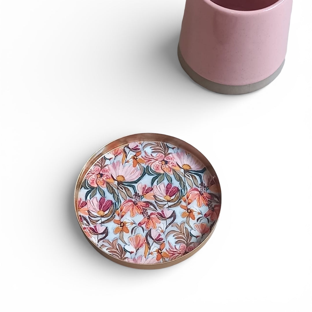 Floral-patterned coaster and a pink mug on a white background