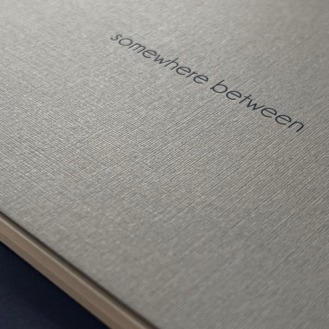 Textured paper with ‘somewhere between’ screen printed on the cover. 